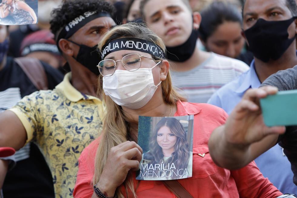 Una seguidora de Marília Mendonça sostiene muy triste una fotografía de la cantante durante el velatorio, en el gimnasio Goiânia Arena. (Foto: Weimer Carvalho / EFE)
