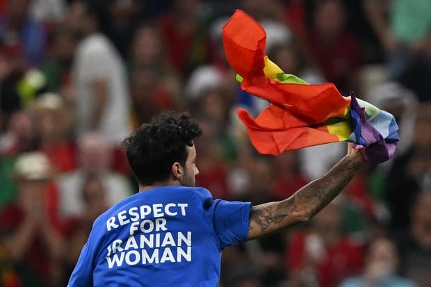 Un hombre con una camiseta que dice "Respeto a la mujer iraní" corre por la cancha agitando una bandera LGBT del arcoíris durante el partido de fútbol del Grupo H de la Copa Mundial de Qatar 2022 entre Portugal y Uruguay en el Estadio Lusail en Lusail, al norte de Doha, el 28 de noviembre. , 2022. (Foto de Pablo PORCIUNCULA / AFP)