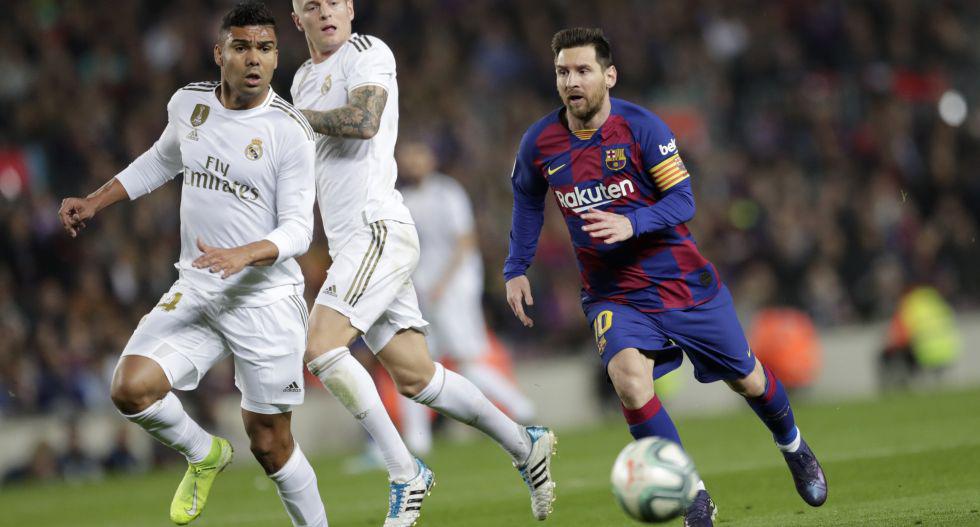 Barcelona's Lionel Messi runs with the ball next to Real Madrid's Casemiro, left, and Toni Kroos during a Spanish La Liga soccer match between Barcelona and Real Madrid at Camp Nou stadium in Barcelona, Spain, Wednesday, Dec. 18, 2019. Thousands of Catalan separatists are planning to protest around and inside Barcelona's Camp Nou Stadium during Wednesday's "Clasico". (AP Photo/Bernat Armangue)