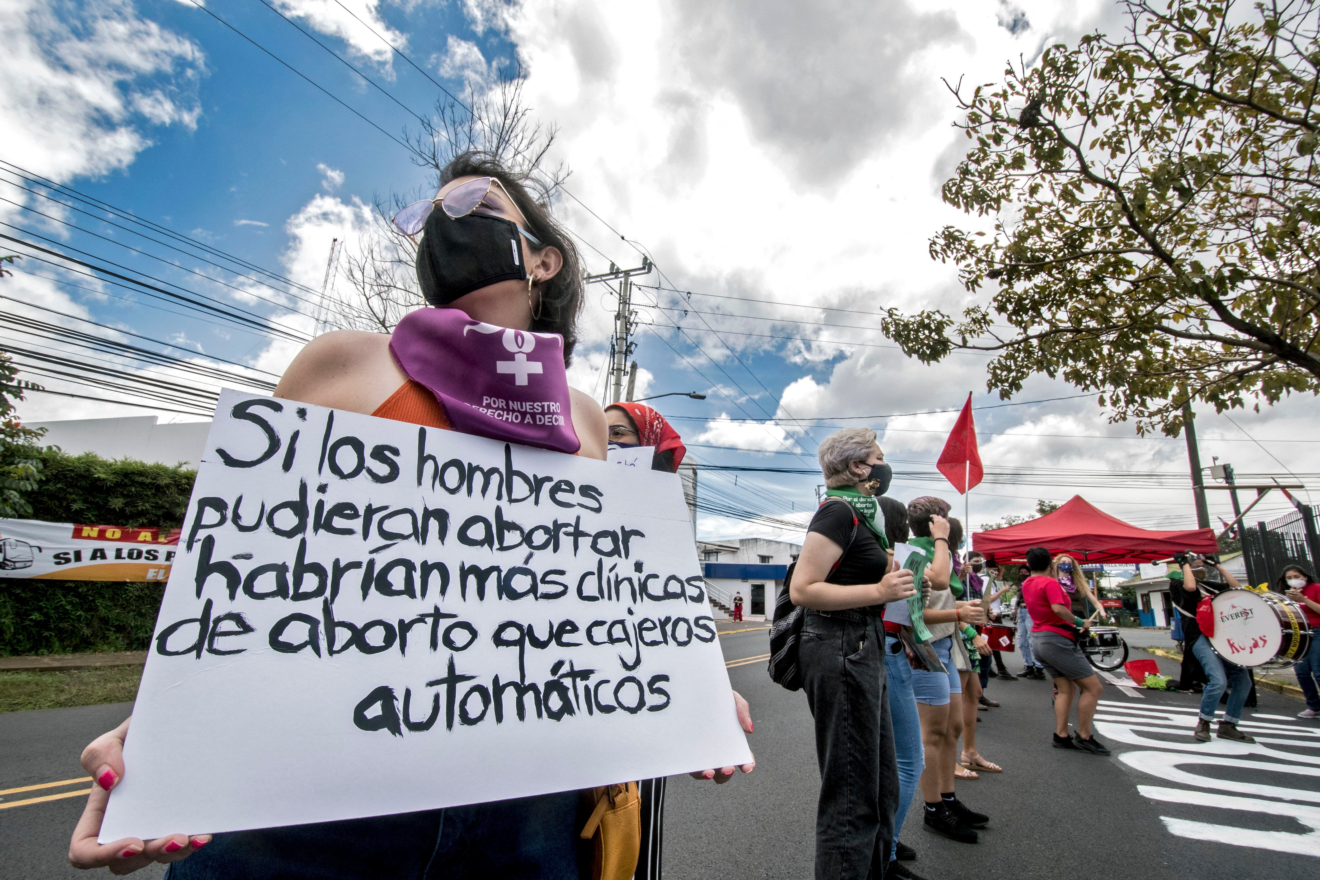 Una mujer sostiene un cartel que dice "Si los hombres pudieran abortar habría más clínicas de aborto que cajeros automáticos", durante una manifestación frente a la casa presidencial a favor de la legalización del aborto, en San José, Costa Rica, el 28 de septiembre de 2020. (Foto: Ezequiel BECERRA / AFP)